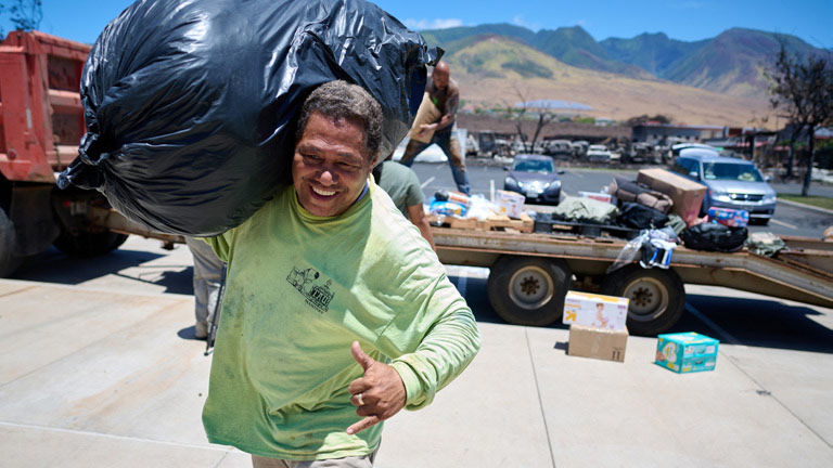 Man carrying garbage bag outside helping with the Maui wildfire cleanup