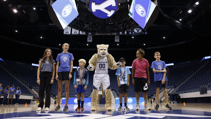 A group of kids with Cosmo Cougar in the Marriott Center