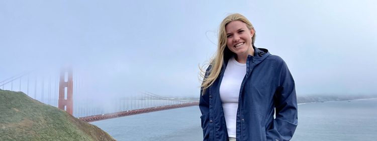 A blonde young women posing for a photo in front of the Golden Gate Bridge