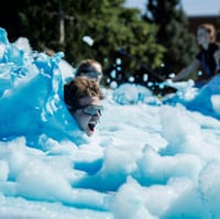BYU student wearing goggles sliding through blue foam