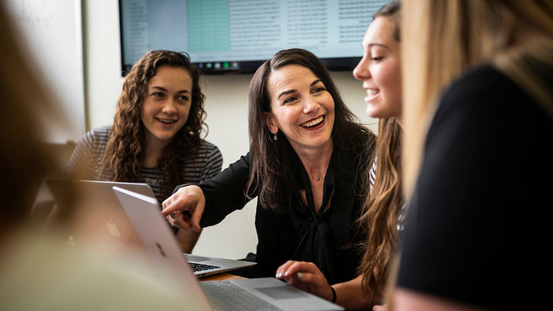 Female teacher showing students something on a laptop