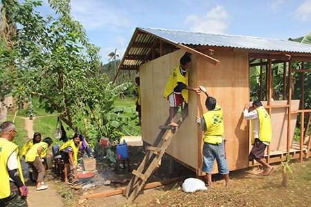 Volunteers nail plywood to the wooden frame of a house under construction in Tacloban, Philippines.