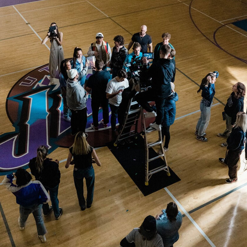 A group of people making a movie on a basketball court.