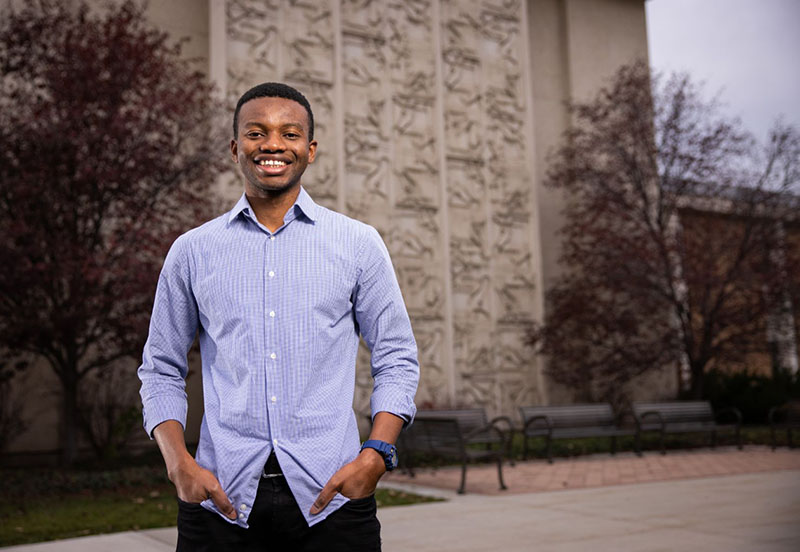 male student standing in front of building