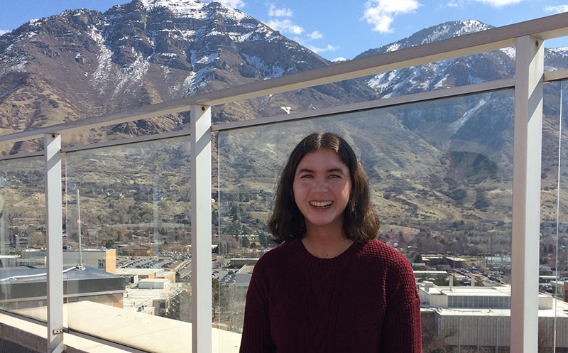 Student on rooftop with snowcapped mountains behind. 