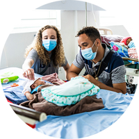 Two BYU nursing students wearing medical face masks checking on a baby