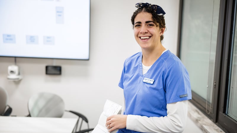 A smiling young woman in nurse’s uniform.