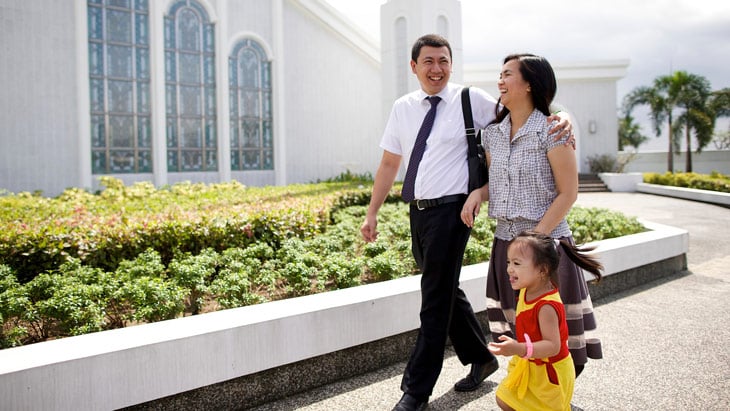 A happy family walking together smiling, a husband and wife and their daughter, outside a temple