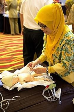 A midwife practices tying the umbilical cord on a baby simulator. 