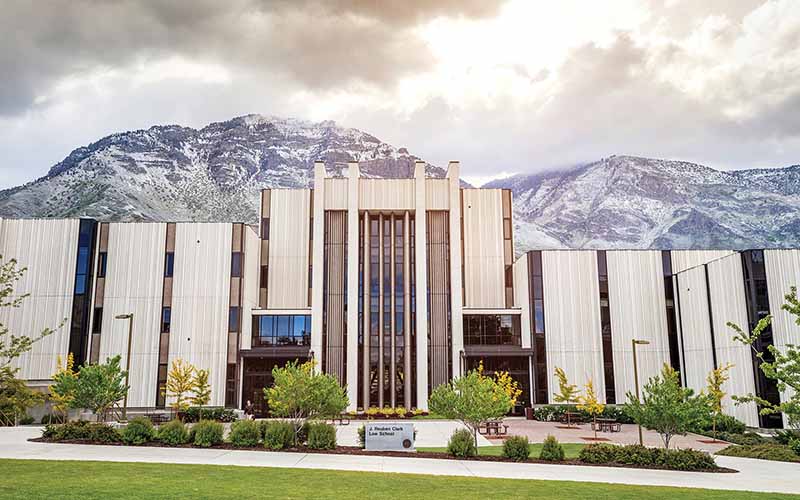 The sun shines over the mountains behind the J. Reuben Clark Law School.