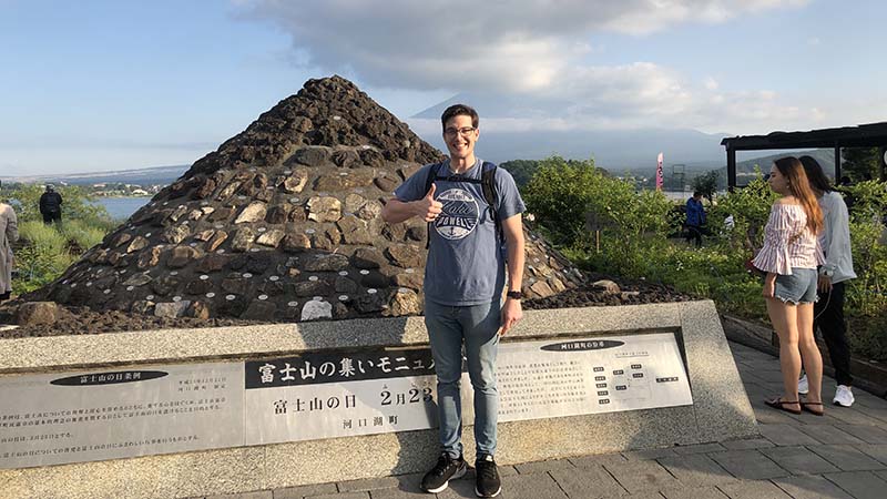 Young man in front of a shrine giving a thumbs up.