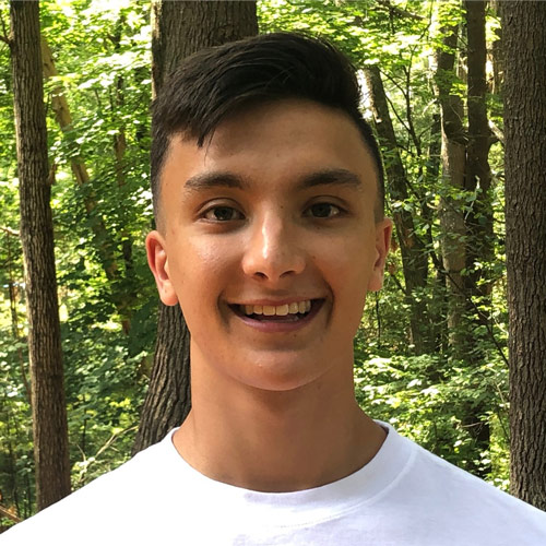 Headshot of recent young man BYU alum with green forest in the background