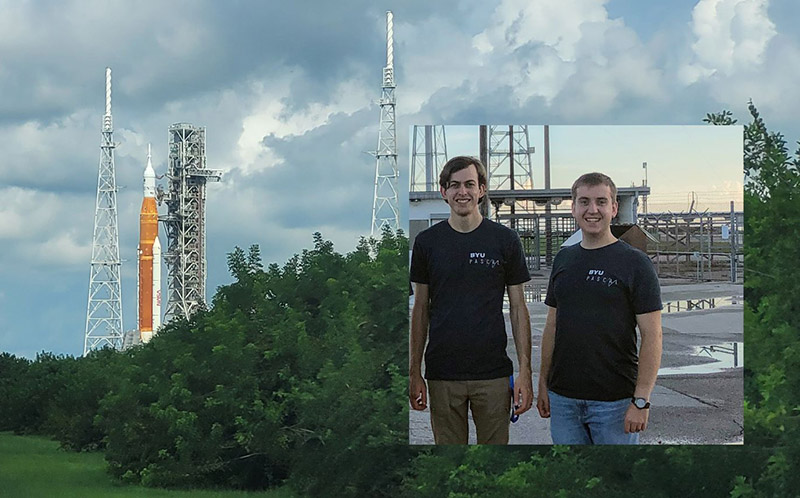 Two students with rocket on launchpad in background 