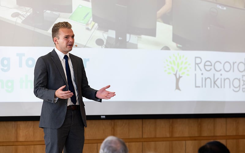 Male student wearing a suit, making a presentation.