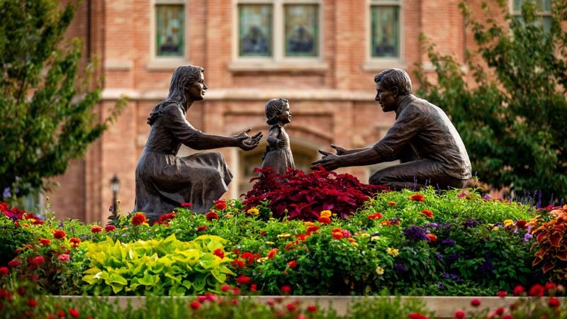 A statue of a man, woman, and child. The adults appear to be helping the child to walk. 