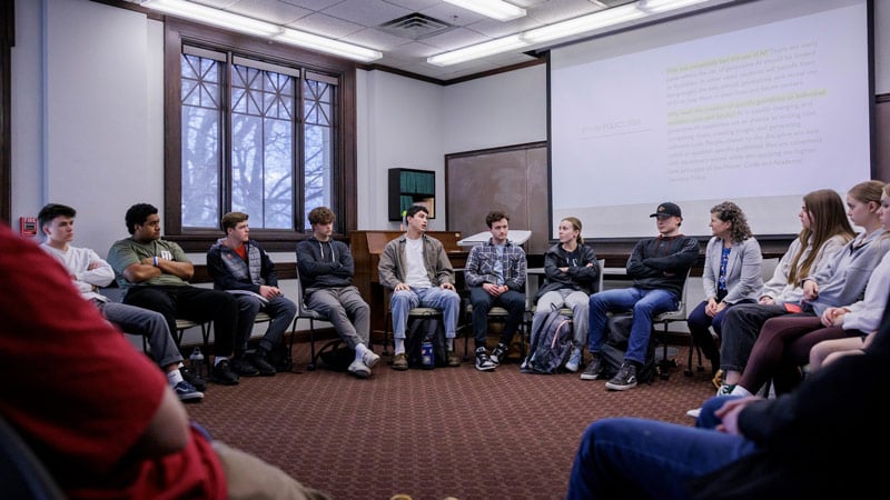 A group of young people sitting in chairs in a circle. 