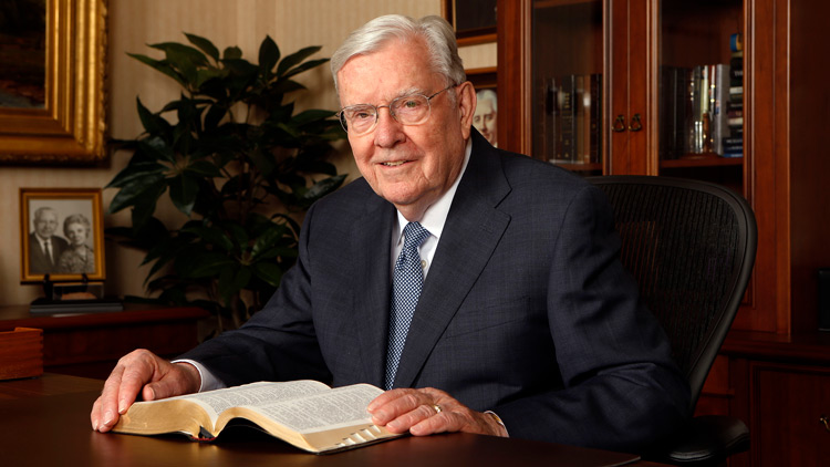 Elder M. Russell Ballard sitting at his desk with scriptures open.