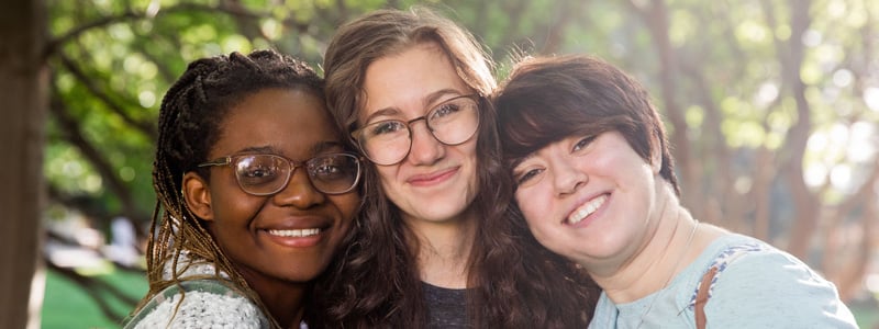Three female BYU-Idaho students smiling outside on the BYU-Idaho campus