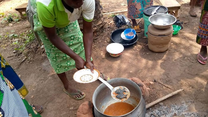African women cooking food using iron fish ingots to boost the iron content in the food.