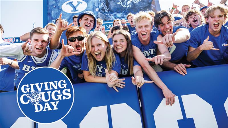 A group of excited and cheering students at a BYU football game with the Giving Cougsday logo in the bottom-left corner