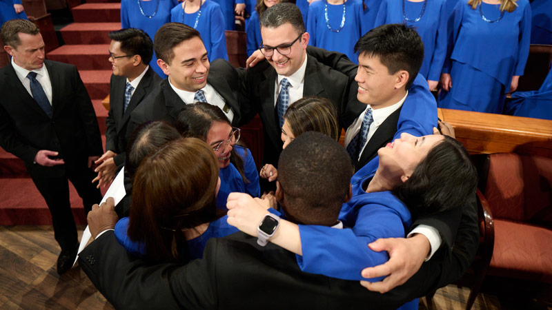 Group of international participants hugging and celebrating after singing at general conference