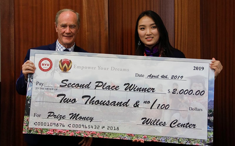 A Mongolian woman being presented with a large check.