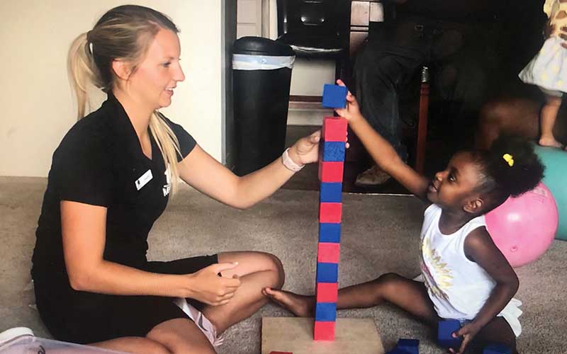 A BYU student builds a block tower with a young girl.