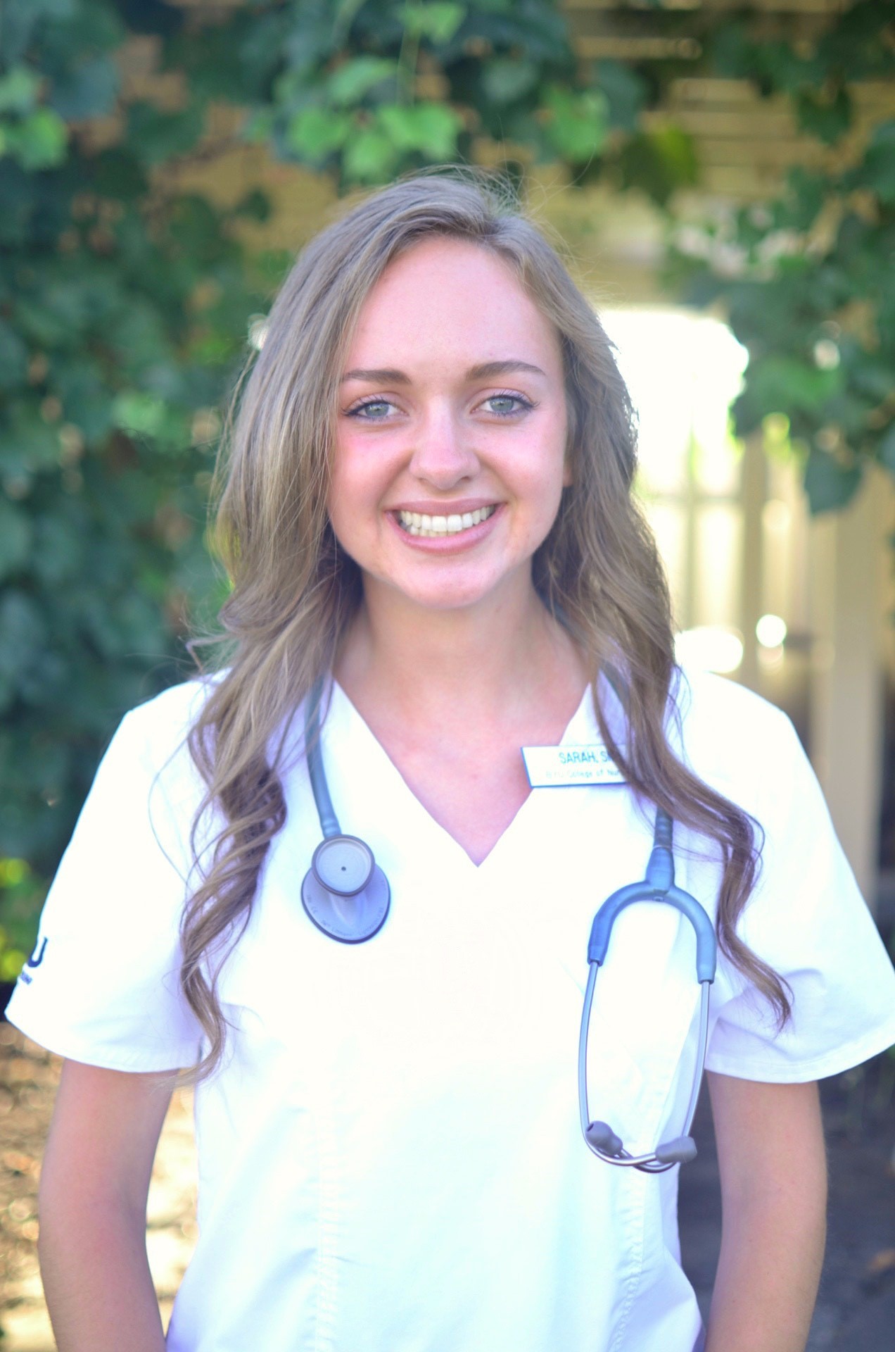 Student nurse with uniform, stethoscope, and nametag.