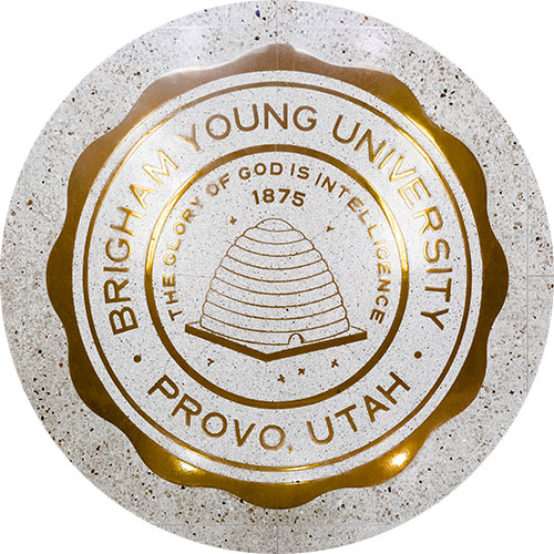 Golden BYU emblem that says "The glory of God is intelligence"