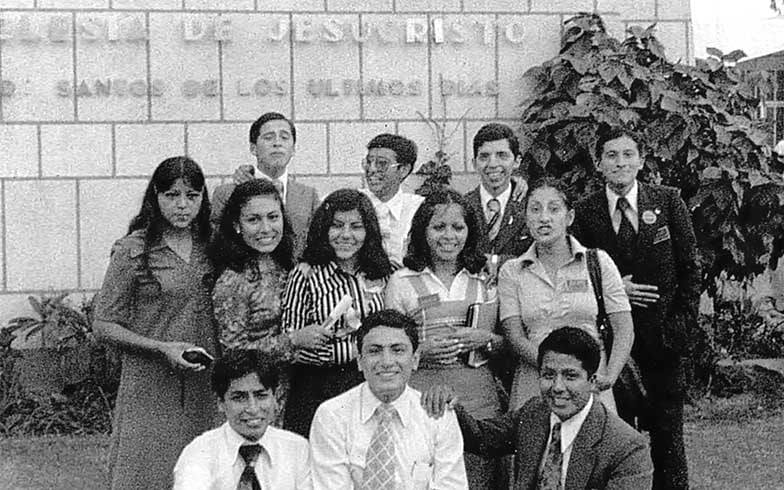 A black and white photo shows Elder Juan A. Uceda as a young missionary, standing outside with a group of fellow missionaries.