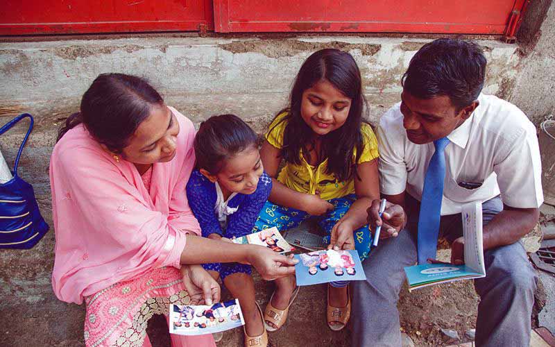 Photo of a mother, father and two daughters smiling as they look down at something out of frame.