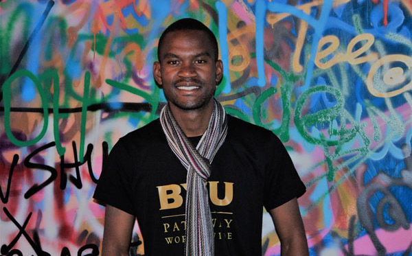 student standing in front of a graffiti wall