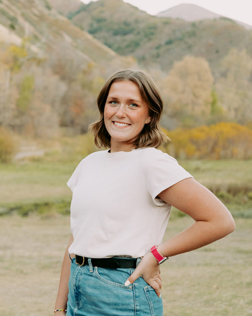 Trevian Frederick, with one hand on her hip, smiling with the mountains behind her