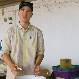 BYU student wearing a yellow shirt cleaning an item found at an archeological dig in Mexico.