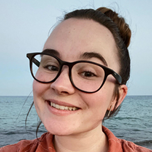 Portrait of a smiling BYU student with ocean waves in the background.