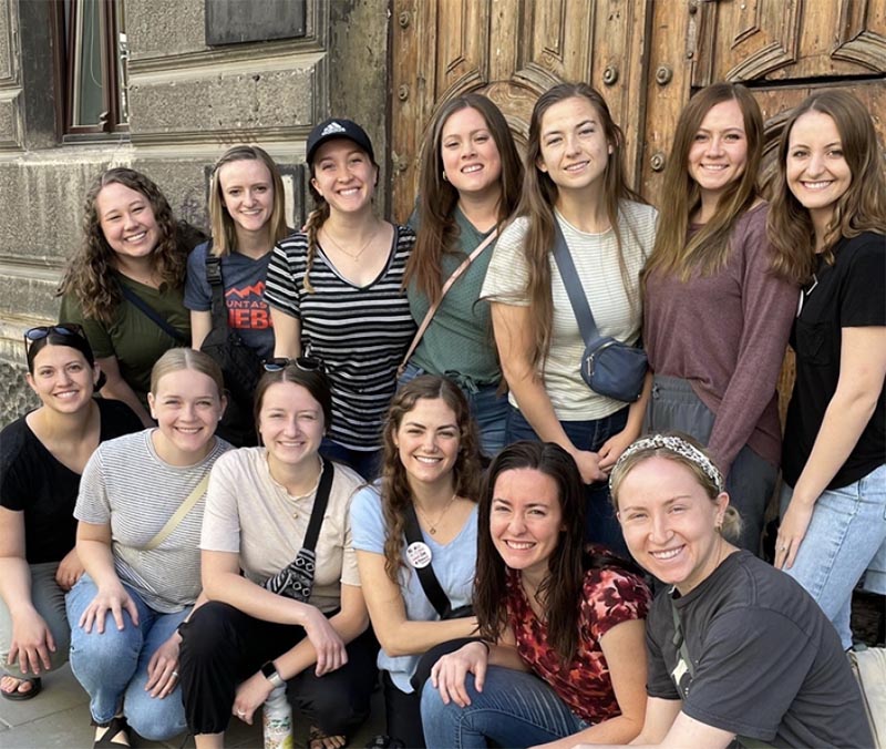 thirteen women standing in front of a building