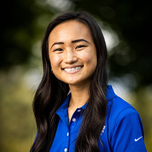 Portrait of a smiling BYU student with long black hair wearing a bright blue golf shirt.